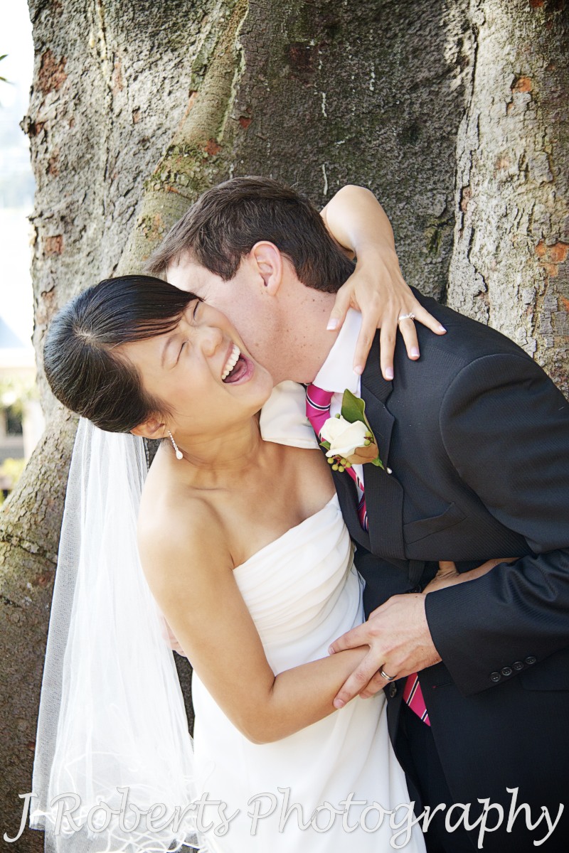 Bride laughing as groom kisses her neck - wedding photography sydney